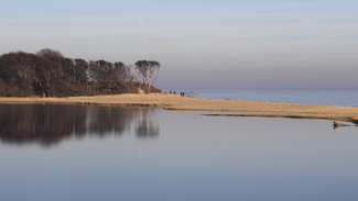 a landscape view of a beach with a small strip separating it from a saline lagoon